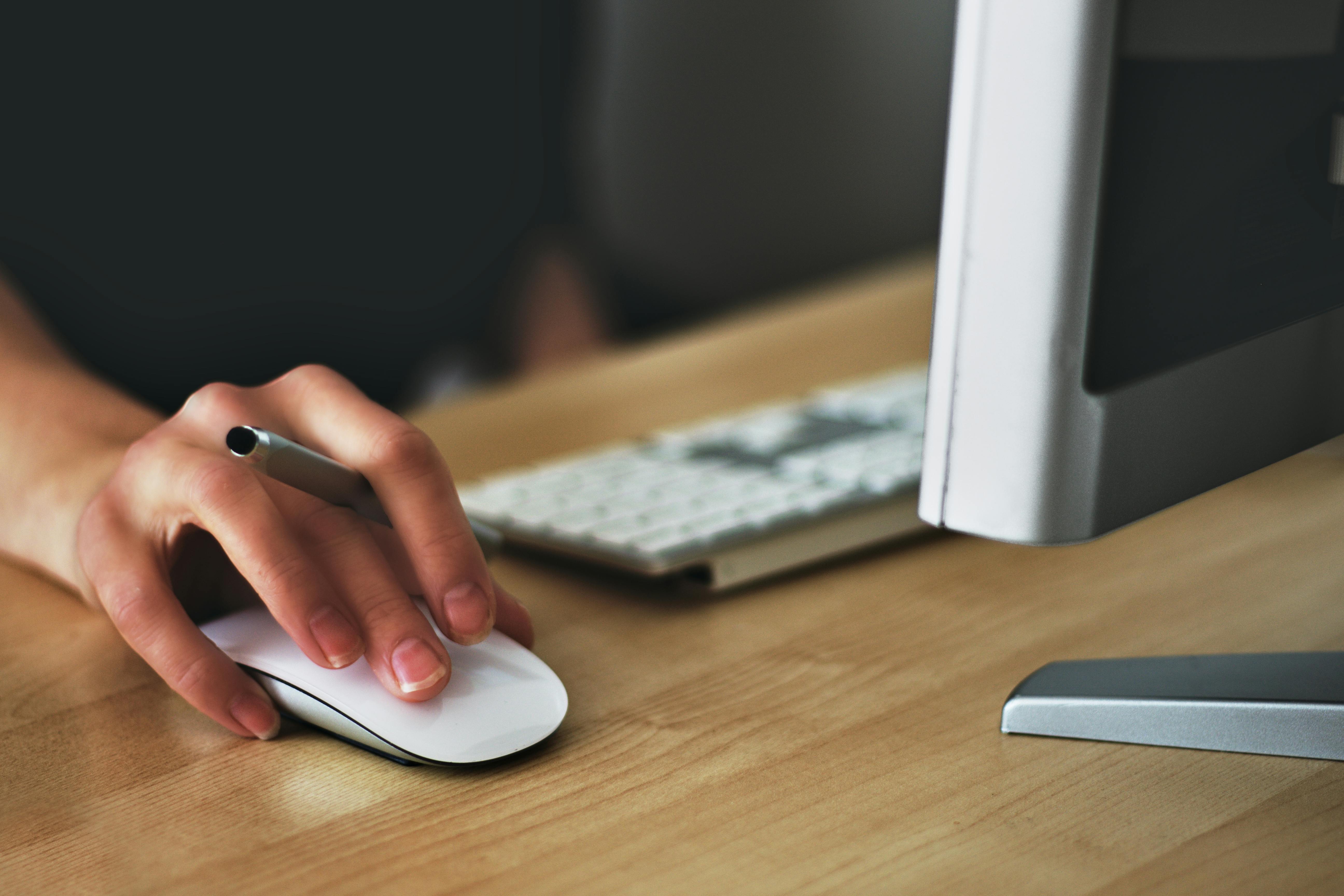 Hand using mouse with desktop computer